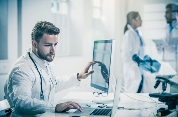 doctor using radiology information systems with colleagues in the background